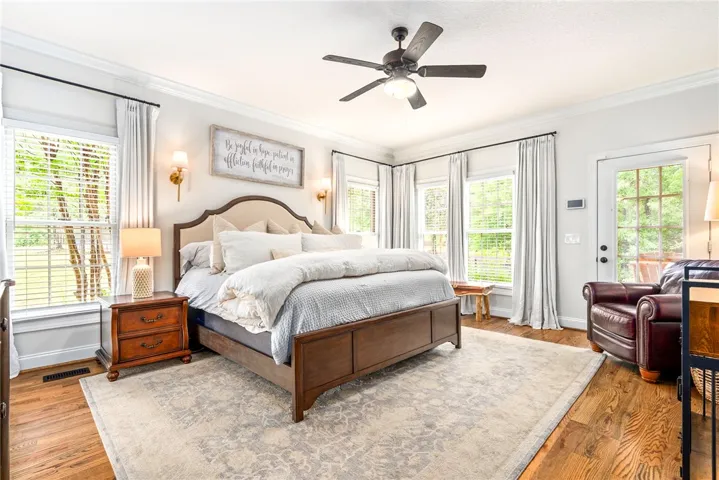 Hardwood flooring extends throughout this naturally illuminated primary bedroom, offering direct access to outdoor spaces.