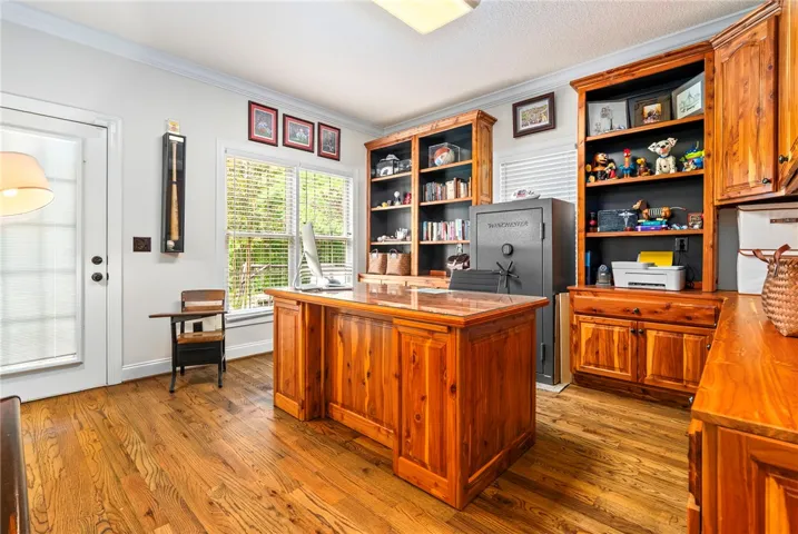 A well-lit home office features rich hardwood flooring and built-in shelving, creating a productive atmosphere.
