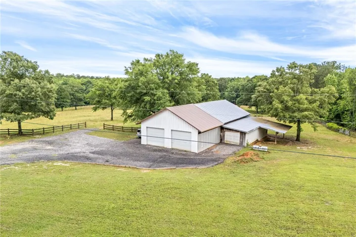A spacious barn and expansive gravel driveway sit amidst a verdant landscape.