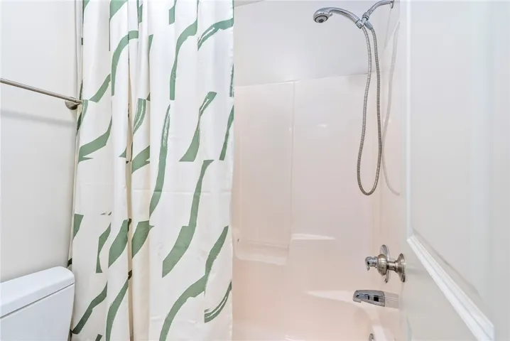 A well-appointed bathroom features a functional shower and a pristine toilet.