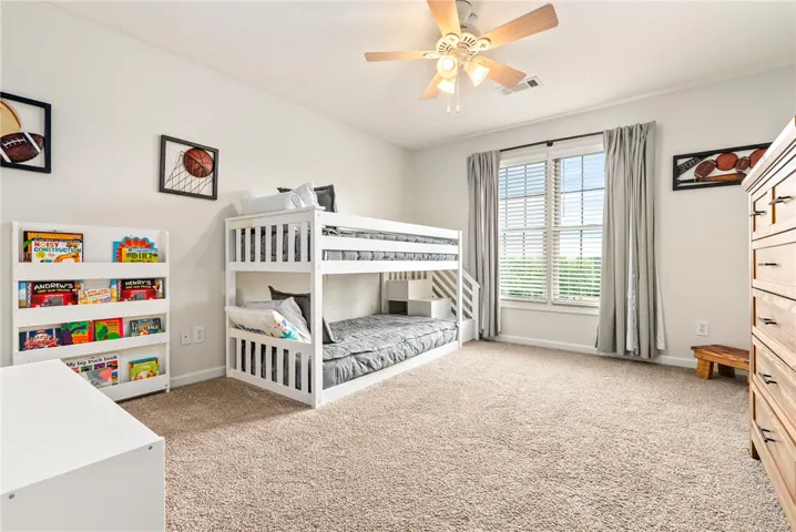 A well-lit bedroom featuring a spacious window and a practical ceiling fan.