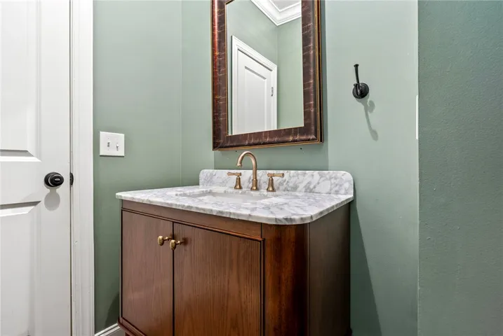 A refined bathroom features a rich wood vanity with a pristine marble countertop and golden fixtures.