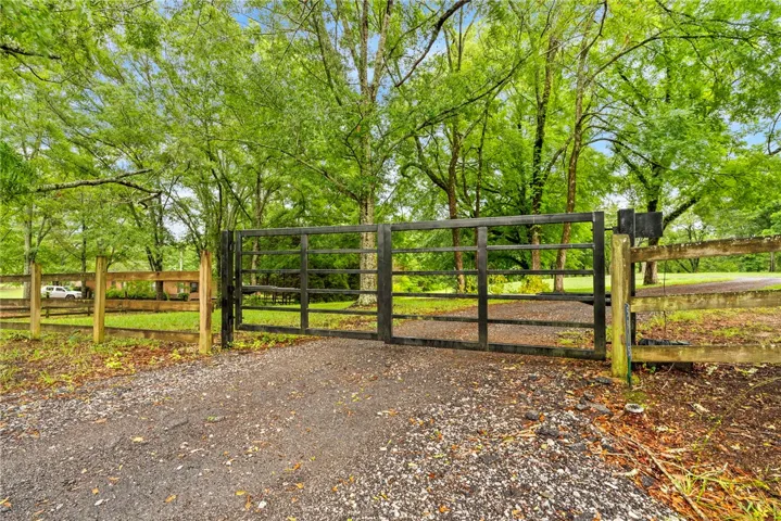 A private, gated entry opens to a serene, tree-lined estate.