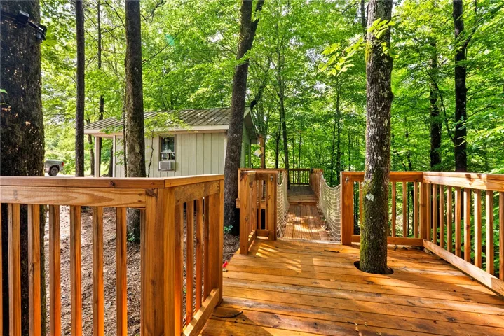 A charming wooden deck winds through a lush forest, connecting to a rustic cabin.