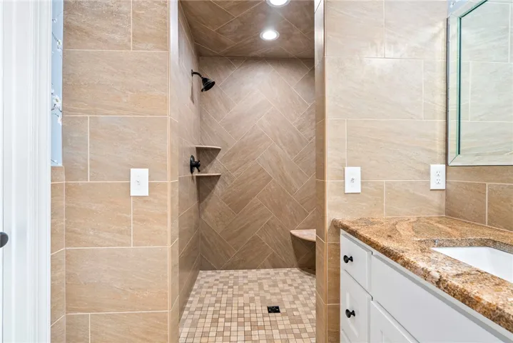 Elegant shower featuring tiled walls and floor, complete with a built-in bench and recessed lighting.