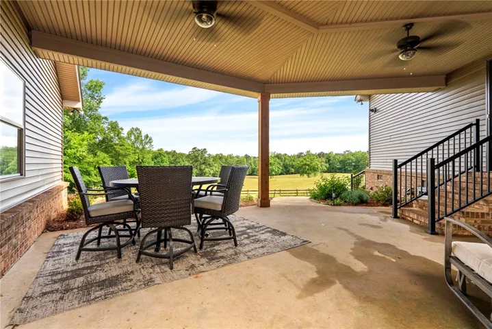 A spacious covered patio invites alfresco living with sweeping views of the verdant landscape.