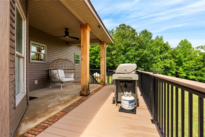 An inviting deck extends from the home, perfect for outdoor cooking and serene tree-lined views.