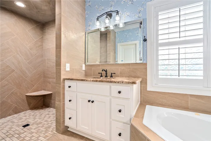 Custom tile work, a single vanity, and an adjacent soaking tub define this elegant bathroom.