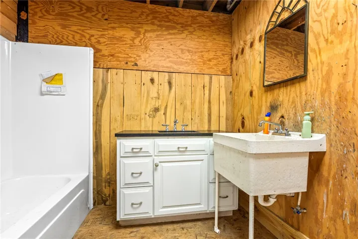 Functional basement bathroom offering a built-in vanity with a sink, an additional utility sink, and a shower/tub combination.
