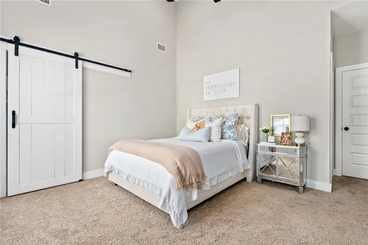 Primary bedroom with vaulted ceiling and barn door leading to walk in closet