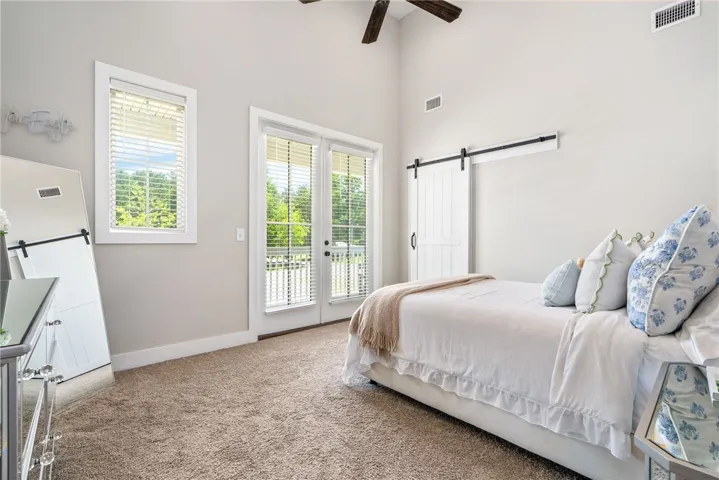 Primary bedroom with vaulted ceiling and barn door leading to walk in closet