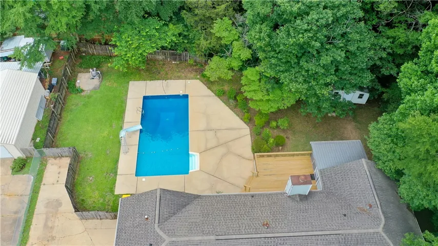 An aerial perspective reveals a sparkling pool, surrounding decking, and a private, backyard.