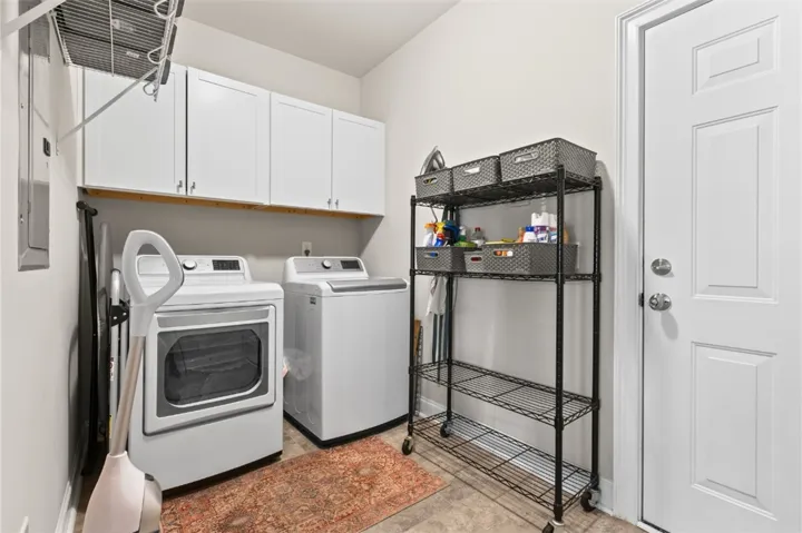 Functional laundry room equipped with upper cabinetry and a wire shelving unit for storage.