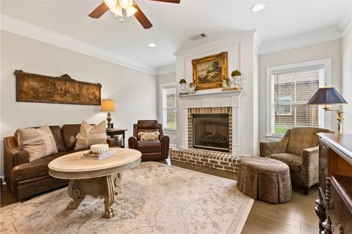 A traditional living area featuring a cozy brick fireplace and rich hardwood flooring.