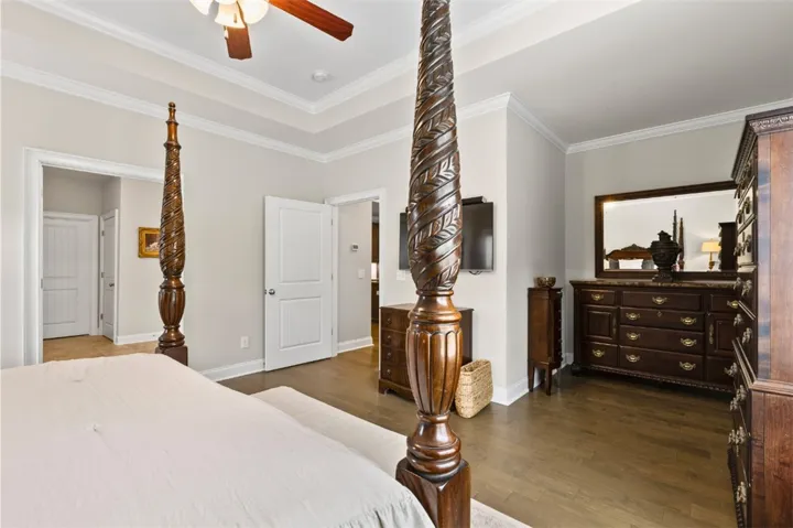 Elegant crown molding and rich hardwood flooring define this primary bedroom's refined aesthetic.