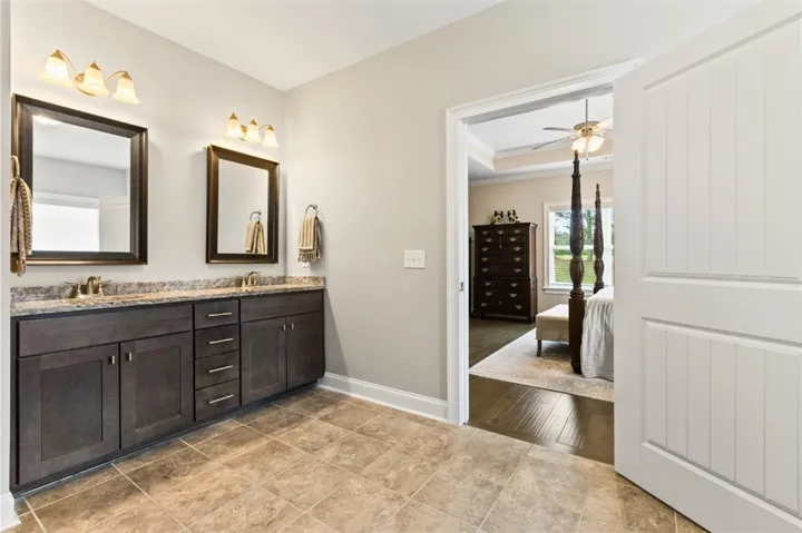 Dual vanities with stone counters offer practical luxury within this well-appointed bathroom.