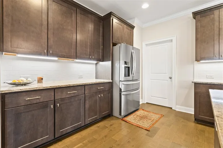 A well-appointed kitchen features rich cabinetry, solid-surface countertops, and bright under-cabinet lighting.