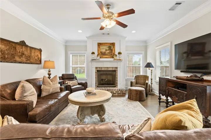 An inviting gathering space features a brick-surround fireplace with a classic mantelpiece and hardwood floors.