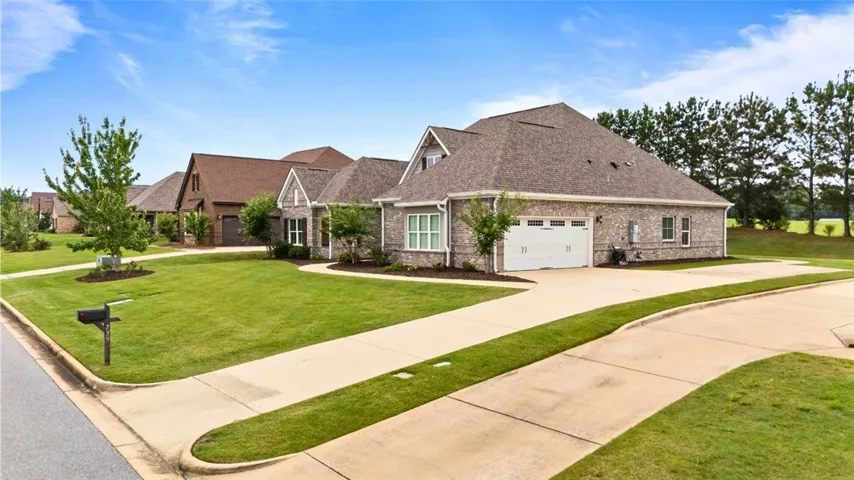 A graceful brick home featuring an attached garage and neatly landscaped yard awaits.