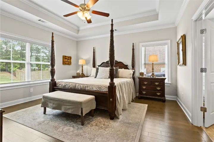 Elegant hardwood flooring grounds a bedroom with high ceilings and a cozy atmosphere.
