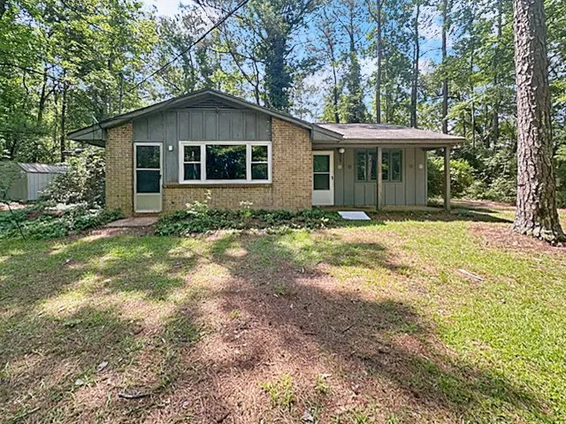 A secluded brick and siding home, nestled amongst mature trees, offers a tranquil forest retreat.