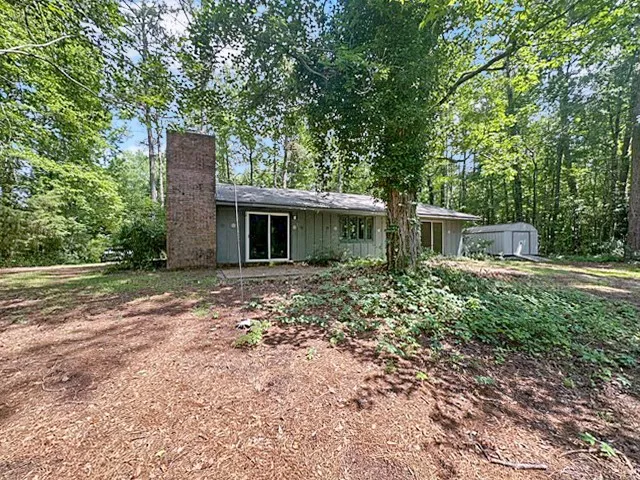 Discover a tranquil woodland retreat with a classic brick chimney and a storage shed.