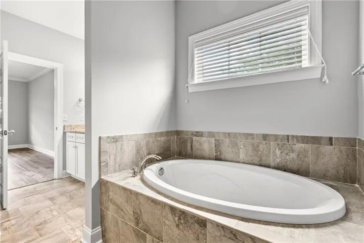 Indulge in a tranquil bathing experience within this well-appointed primary bathroom, featuring a deep soaking tub and elegant tile surrounds.