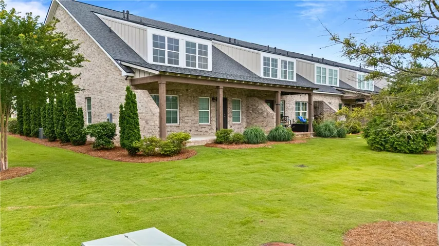 A neatly maintained yard and covered patio enhance the inviting rear facade of this residence.