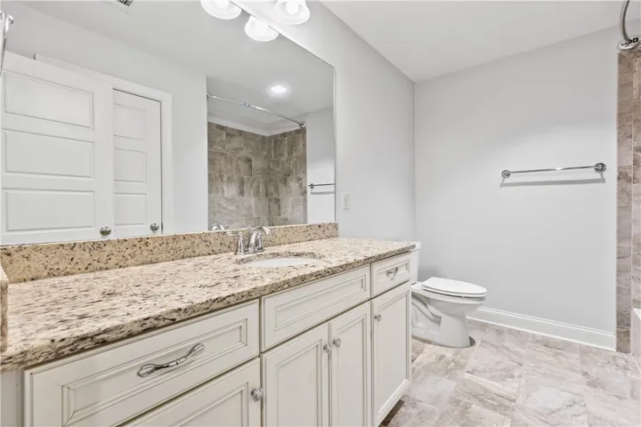A well-appointed bath features a spacious granite vanity and sleek tiled flooring.