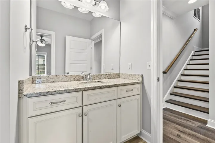 A well-appointed vanity with generous granite counter space is perfectly positioned beside a modern staircase.