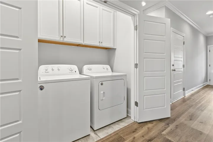 Functional laundry space featuring modern appliances and upper cabinetry for organized storage.