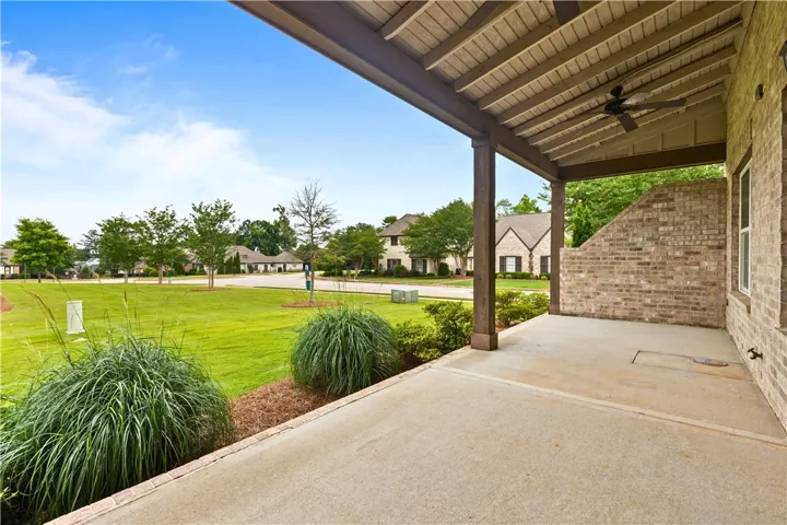 A spacious covered patio invites relaxation, overlooking a manicured community green space.