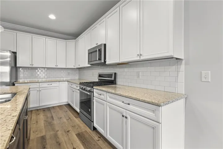 Culinary creations come to life in this kitchen, featuring white cabinetry and granite countertops.
