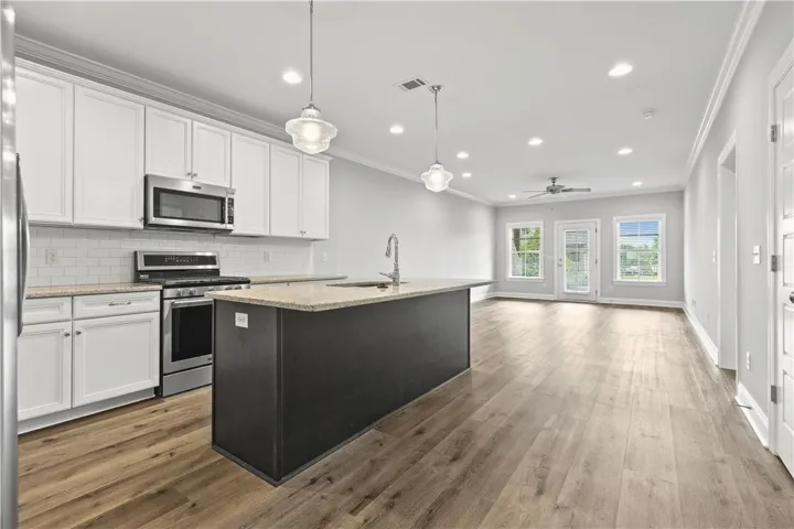 A streamlined open-concept kitchen and living area feature wood-look flooring and recessed lighting.