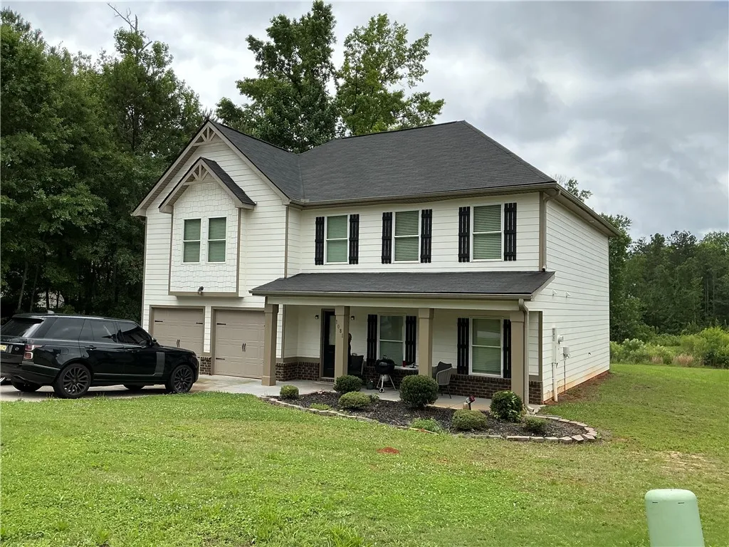 A classic two-story residence presents a welcoming facade with a covered porch and attached garages.