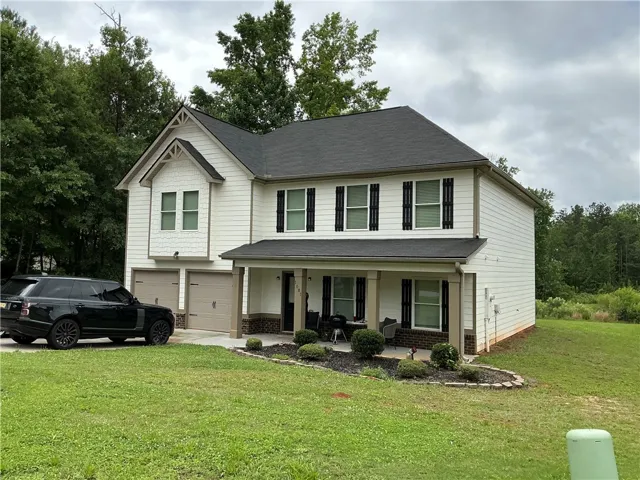 A classic two-story residence presents a welcoming facade with a covered porch and attached garages.