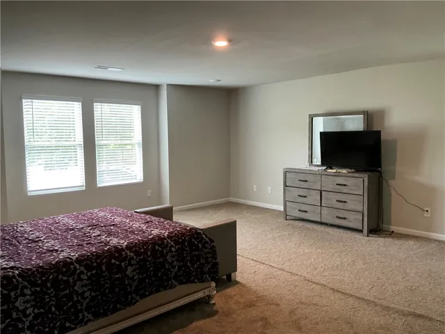 An inviting bedroom offers ample space and warm, carpeted flooring for ultimate comfort.
