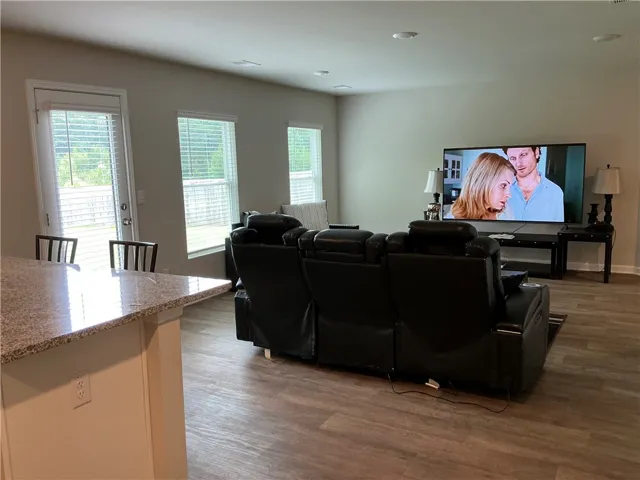 Laminate flooring graces this open-concept living space, featuring a functional kitchen island and bright windows.