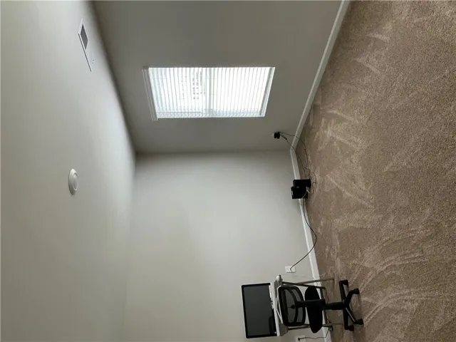 A well-lit room offers ample natural light and plush carpeting.