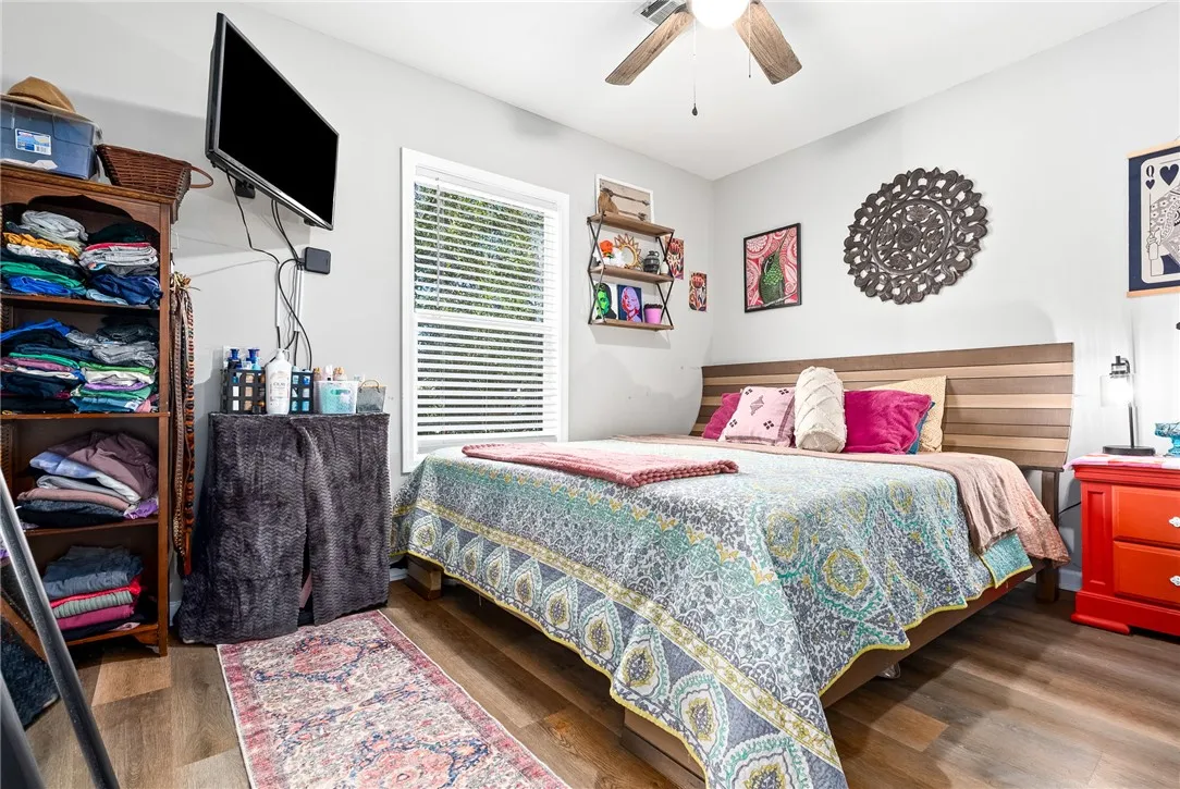 A well-lit bedroom featuring durable plank flooring and a classic ceiling fan for optimal comfort.