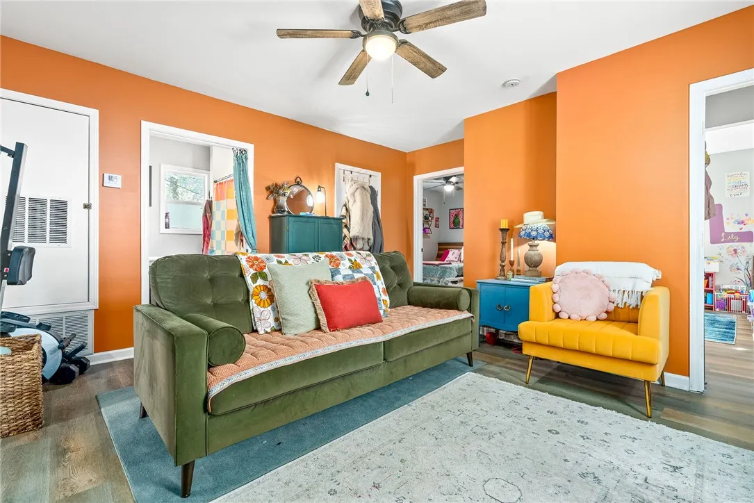 Bright orange walls define this cozy living area, featuring rich wood flooring throughout.
