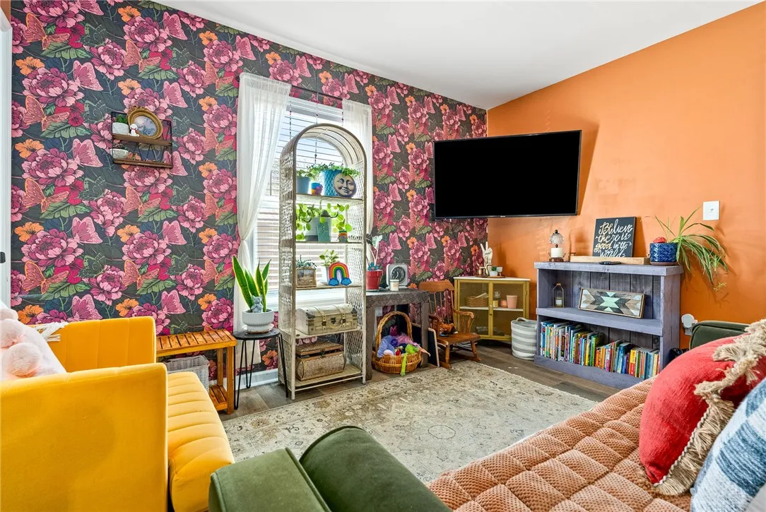 Bold floral wallpaper accents this cozy living space with rich hardwood-style flooring.
