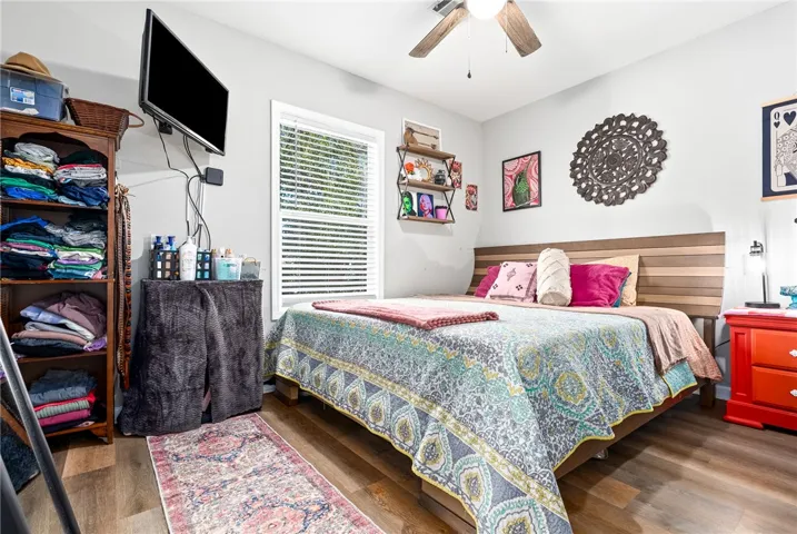 A well-lit bedroom featuring durable plank flooring and a classic ceiling fan for optimal comfort.