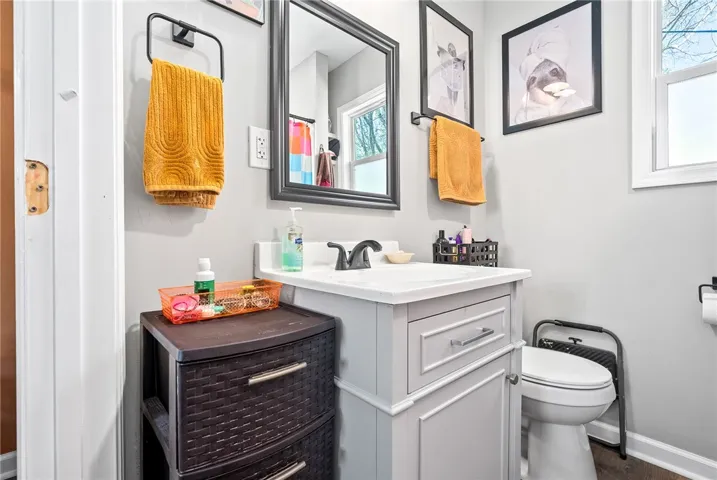 A compact and functional bath space with a clean vanity, mirror, and a clear window offering natural light.