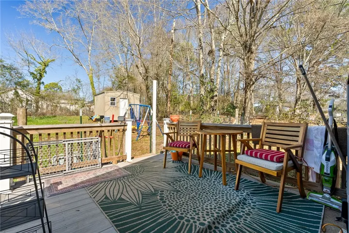 Relax on the ample wooden deck overlooking a fenced yard with mature trees.