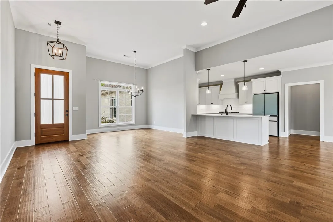 Hardwood floors stretch across this open-concept layout, connecting the living area and dining area to a modern kitchen.