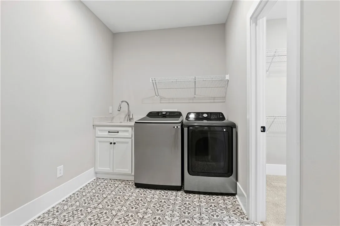 Functional laundry room featuring a utility sink for convenience and cute tiles!