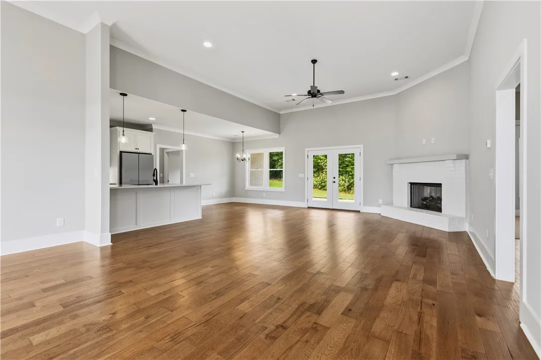 Hardwood floors stretch across a light-filled open-concept space featuring a sleek kitchen and a cozy fireplace.