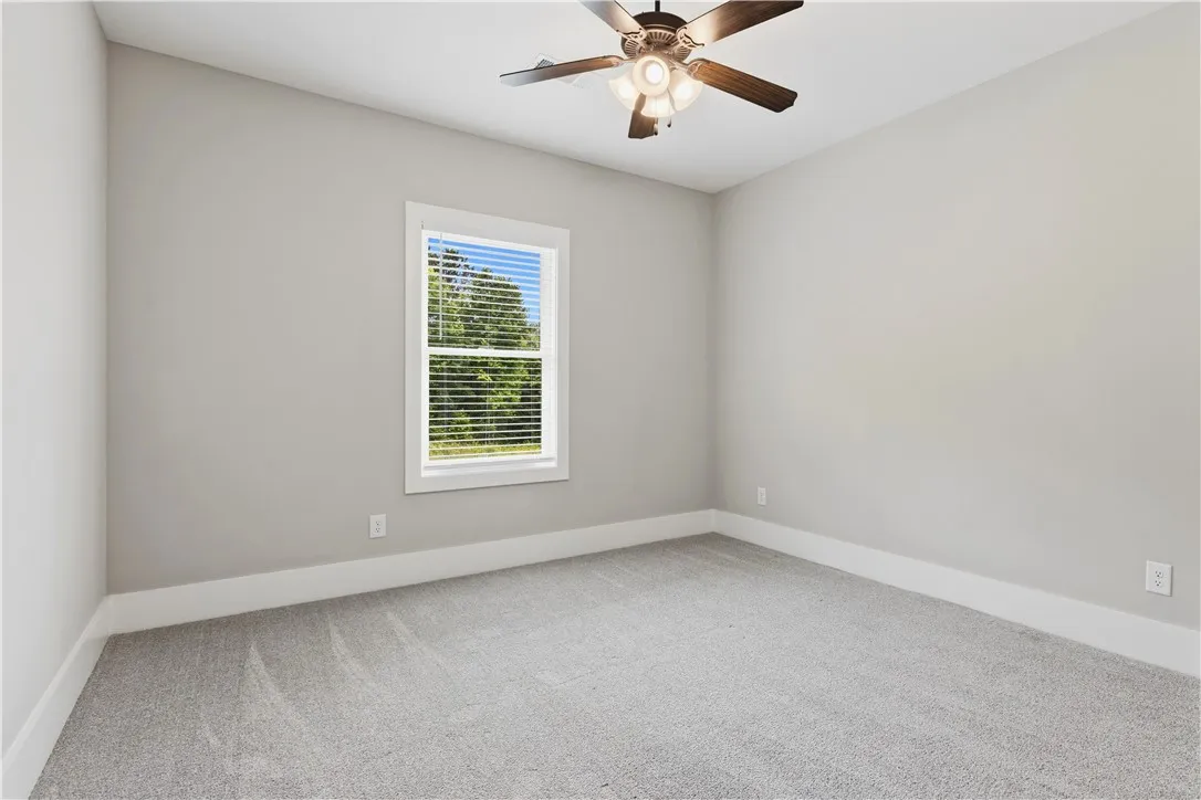 A well-lit room showcasing plush carpeting and a modern ceiling fan.