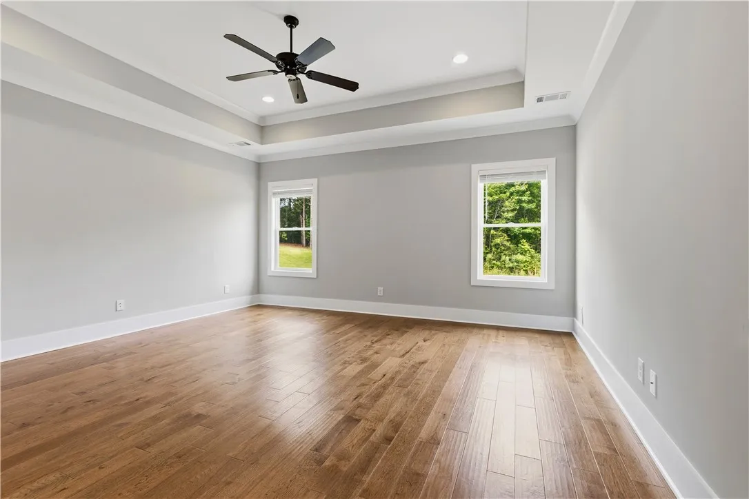 An airy bedroom with gleaming hardwood flooring offers serene tree-lined views.